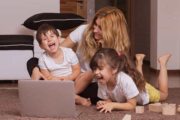 About us Adult and children smiling while watching a laptop together during an Active Therapy Services occupational therapy session in Adelaide.