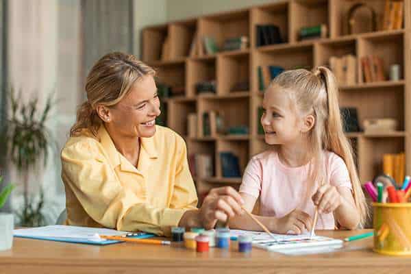 About us Adult and child smiling while painting together during an Active Therapy Services occupational therapy session in Adelaide.